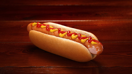 Classic hot dog with ketchup and mustard on a background of wooden boards.