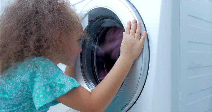Cute Child Looks Inside the Washing Machine. Cylinder Spinning Machine. Concept Laundry Washing Machine, Industry Laundry Service.
