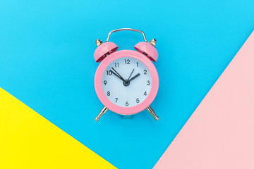 Ringing twin bell classic alarm clock isolated on blue yellow pink pastel colorful geometric background. Rest hours time of life good morning night wake up awake concept. Flat lay top view copy space
