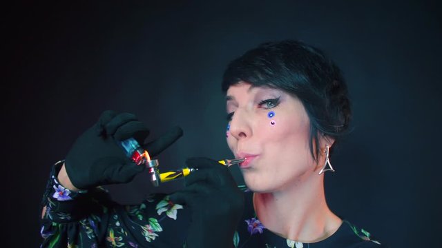 Girl smokes a pipe at a party in a nightclub.
