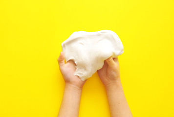 Child hands with slime on yellow background.