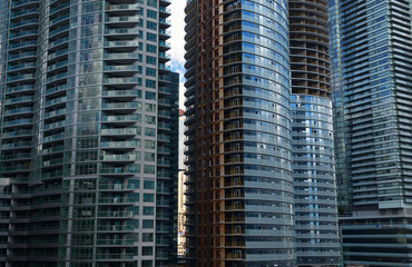 Obraz na płótnie Canvas View of golden bank towers through slit in crowded highrise condominium construction in Toronto