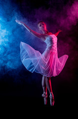 Ballerina dancing in colored smoke. dancer in motion with the effects of highlighting with color...