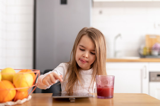 Young girl eating cookies and playing on her tablet