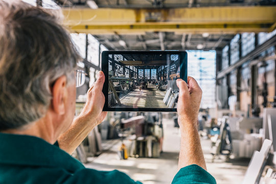 Senior Man Holding Tablet Computer at Work taking a photograph