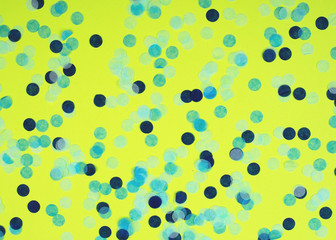 Festive multicolored confetti scattered on yellow background. Holiday concept. Pastel polka dots texture.
