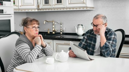 Confident senior man drinking morning tea reading newspaper having breakfast with wife - Powered by Adobe
