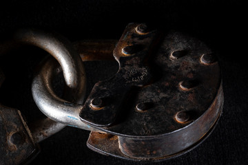 Old rusty vintage padlock on dark stone background. Macro shot. Close up, copy space