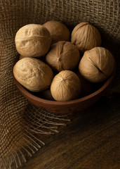 Walnuts in clay plateon wooden table with textile. Vertical photo