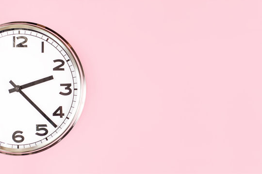 Part of big analogue plain wall clock on candy pink background. Close up with copy space, time management concept and lunch time