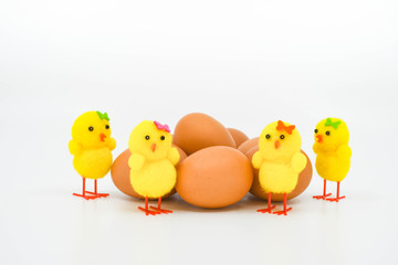 Close up of yellows chick made of foam standing around a clutch of fresh brown eggs.