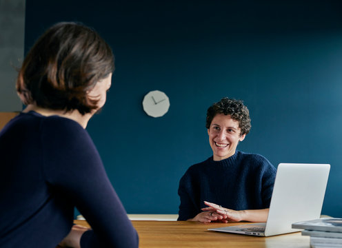 Two smiling women working together in a modern office.