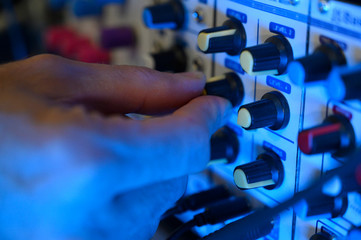 Man's hand adjusting the volume of a synthesizer