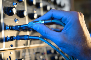 Man's hand adjusting something in a music synthesizer.