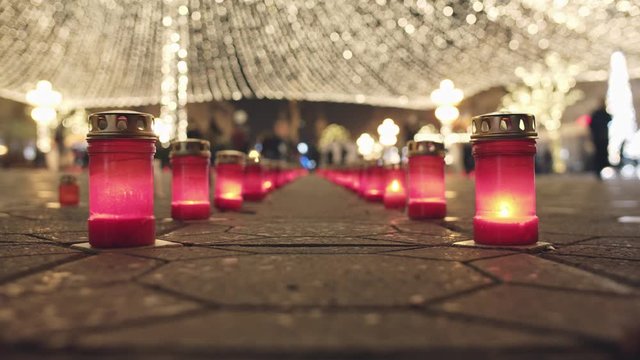 The candles lit in a row in Piata Victoriei - Victory Square in Timisoara commemorating 30 years since the romanian revolution in 1989 and the fall of communism, and Christmas Lights in background