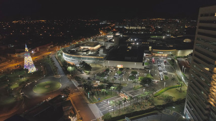Aerial view at night over Ribeirão Shopping, the largest mall in Ribeirão Preto city, Brazil. December, large Christmas tree. 4K.
