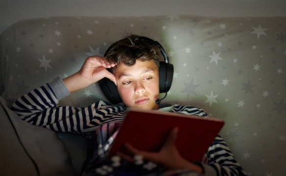 Boy in headphones using tablet on sofa