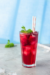 Tea with hibiscus, berries (raspberries and blackberries), mint, lime, lemon and ice in the sun with shadows. Trendy style with artistic shadows.