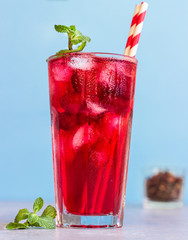 Iced hibiscus tea (karkade, red sorrel, Agua de flor de Jamaica) or lemonade with raspberries and mint on a light grey background. 