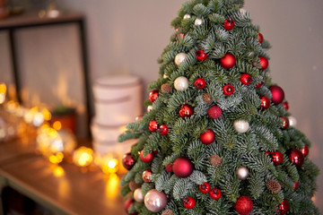 Beautiful small Christmas tree on wooden table. Happy mood. Garland lamp bokeh on background. Wallpaper. Danish pine and fir, Nobilis