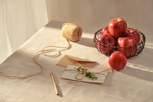 A letter and red apples on table.