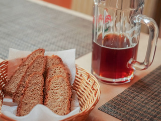 Slices of bread in a basket, glass of beer on a table in a restaurant.