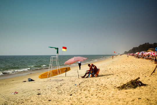 Typical beach in Goa, India, view towards the sea, golden sand, blue sky. Indian lifeguards on duty.