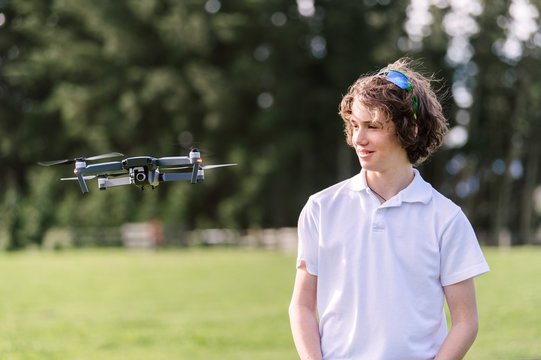 Teenage boy standing next to a flying drone