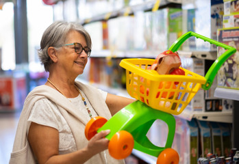 A beautiful grandmother examines a toy to buy for her granddaughter. Pay attention to the price and...