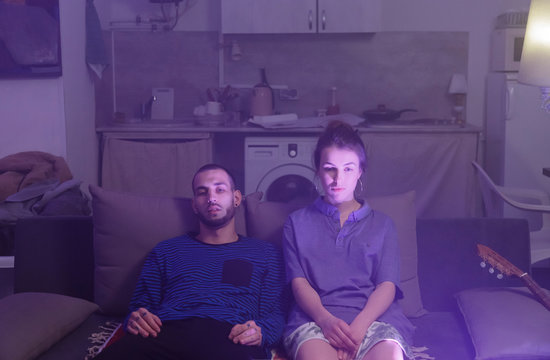 Tired couple watching TV in evening