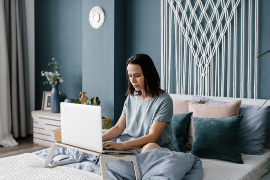 Focused woman using laptop on bed