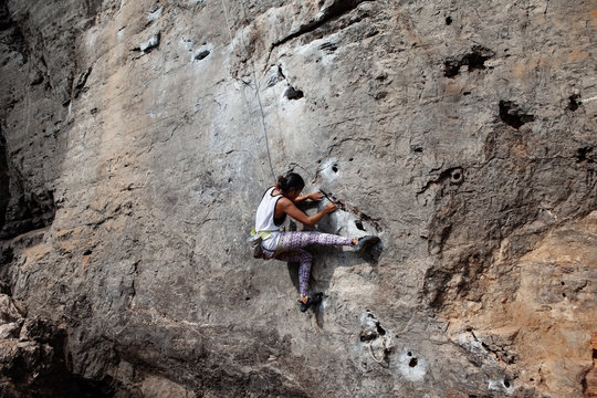 Athletic woman climbing cliff