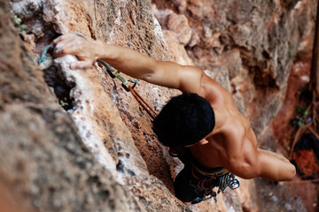 Muscular climber hanging on rock