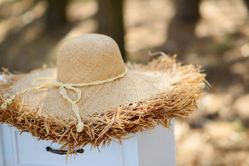 Beautiful white chest of drawers with a straw hat in the forest. Boho style girl party.