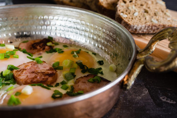 fried eggs with sausages in a copper frying pan