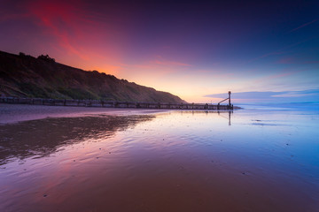 Sunset colours with wet reflections on the beach in Mundesley, North Norfolk, UK