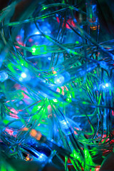 Blurred close-up photo of a multi-colored Christmas electric garland. Shining holiday lights of blue, green and red LED lamps with a transparent wire, bright color image.