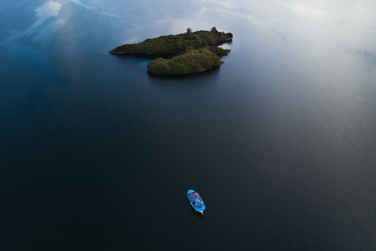 Aerial view of a small island and a blue boat on the sea