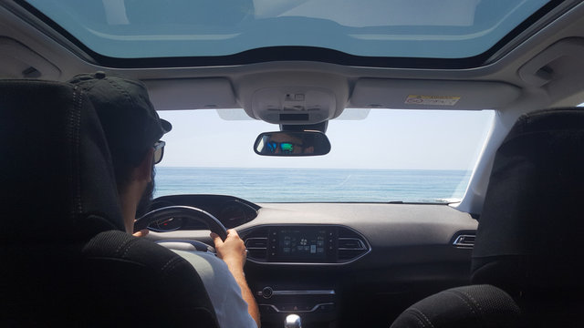 Young man driving his car to the beach