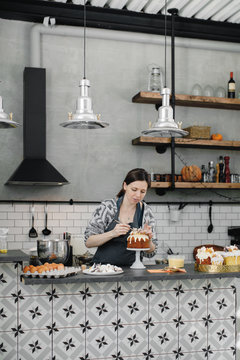Woman decorating fresh biscuits in kitchen