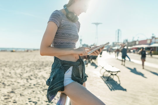 Young Woman Using a Mobile Phone on the Beach Outdoor . Technology stock Picture