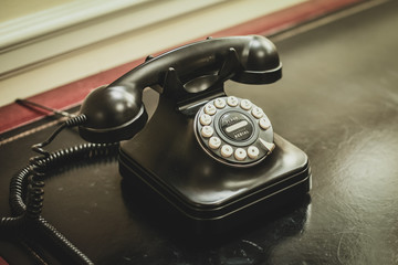 An old vintage phone sitting on an office desk. A rotary dial oldtimer telephone.