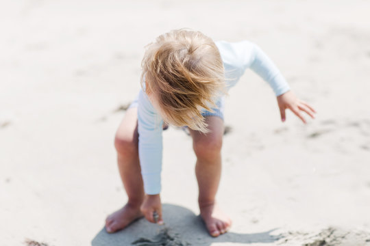 windblown hair of a toddler playing on the beach