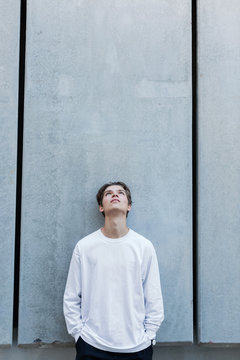 A Young Man Stands Against A Gray Wall