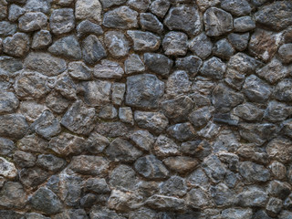 Stone wall of dark rough cobblestone.