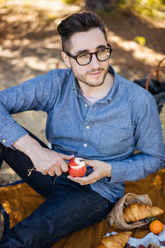 Human sitting on coverlet and cutting apple