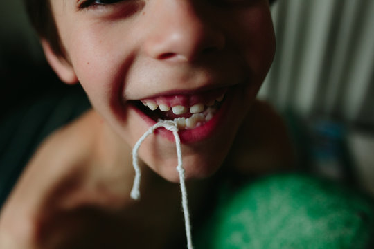 boy ties string around loose tooth