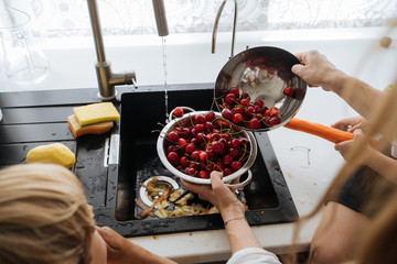 Crop mother washing berries for kids