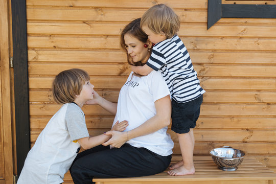 Sons and pregnant mother near house