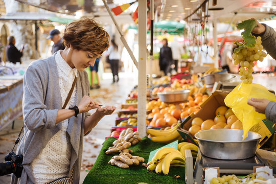 Person with camera near fruits counting coins